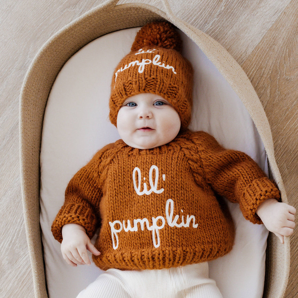 Baby wearing a rust-colored Lil Pumpkin knit outfit and matching hat