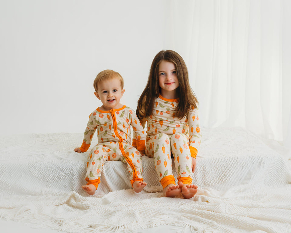 Two children wearing Little Sprouts pajamas: a zippy and a matching two-piece set
