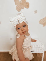 Baby modeling white bow turban with eyelet detail — front