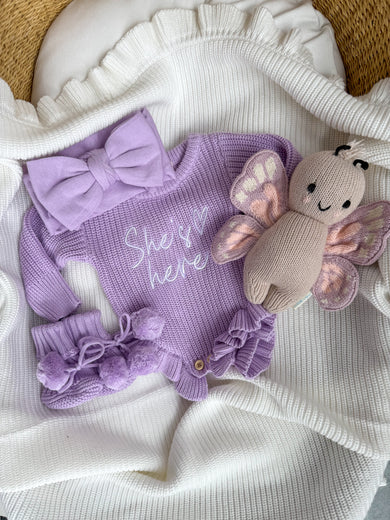 Orchid purple pompom booties for baby styled with matching outfit, close-up of cotton knit texture