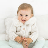 Side view of natural knit baby cardigan with fur collar showing button placement and fit