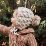 Close-up detail of cable knit pattern on oatmeal baby bonnet showing premium cotton construction