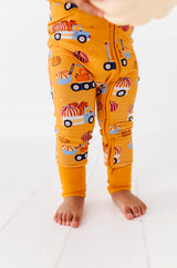 Close-up of the Let the Gourd Times Roll footie showing pumpkin-and-truck print and open ankle cuffs.