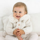 Detailed close-up of natural baby cardigan knit pattern and fur collar construction quality