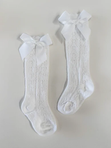 White Spanish openwork lace knee high bow socks styled on baby, showing full knee-high length