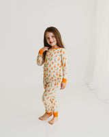Smiling girl standing in Little Sprouts Soluna bamboo two-piece pajamas with orange cuffs