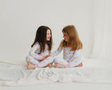 Two girls sitting together in matching Royal Ducklings Soluna bamboo two-piece pajamas