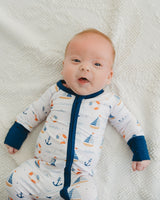 Smiling newborn baby lying on cream blanket in Harbor Dreams Soluna bamboo zippy with navy cuffs
