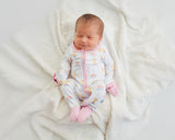 Newborn baby smiling in Royal Ducklings Soluna bamboo zippy on cream blanket