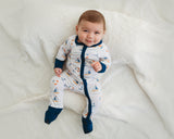 Baby lounging on white blanket in Harbor Dreams Soluna bamboo zippy with sailboat print