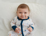 Smiling baby sitting on white blanket in Harbor Dreams Soluna bamboo zippy with navy cuffs