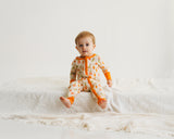 Baby sitting on white blanket in Little Sprouts Soluna bamboo zippy with orange cuffs