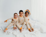 Girl and baby wearing matching Little Sprouts Soluna bamboo two-piece pajamas and zippy on white bed