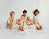 Children and babies wearing matching Little Sprouts Soluna bamboo pajamas and zippies on white bed