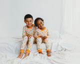 Two smiling children sitting in matching Little Sprouts Soluna bamboo two-piece pajamas