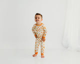 Smiling boy standing in Little Sprouts Soluna bamboo two-piece pajamas with orange cuffs