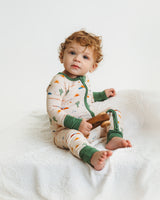 Baby sitting in Desert Dawn Soluna bamboo zippy with sage cuffs holding wooden toy