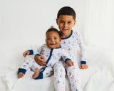 Boy and baby wearing matching Harbor Dreams Soluna bamboo pajamas and zippy on white bed
