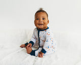 Smiling baby sitting in Harbor Dreams Soluna bamboo zippy with navy cuffs