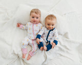 Two babies wearing Royal Ducklings and Harbor Dreams Soluna bamboo zippies on a white blanket
