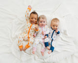 Babies wearing Royal Ducklings, Little Sprouts, and Harbor Dreams Soluna bamboo zippies on a white blanket