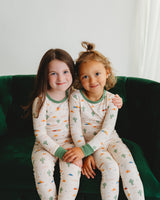 Two girls wearing Desert Dawn Soluna bamboo pajamas on a green velvet couch