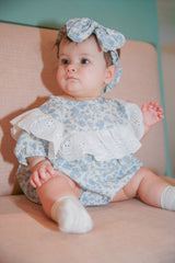 Baby girl in blue floral eyelet lace romper with matching bow headband - front sitting pose