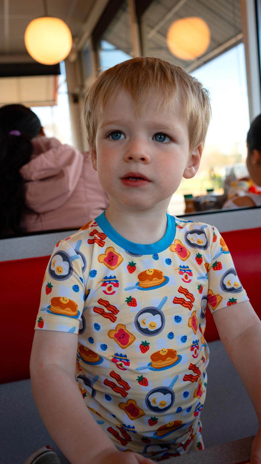 Little girl wearing Breakfast Buddies bamboo pajama top at breakfast table