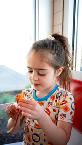 Child in Breakfast Buddies bamboo pajama top eating breakfast by window