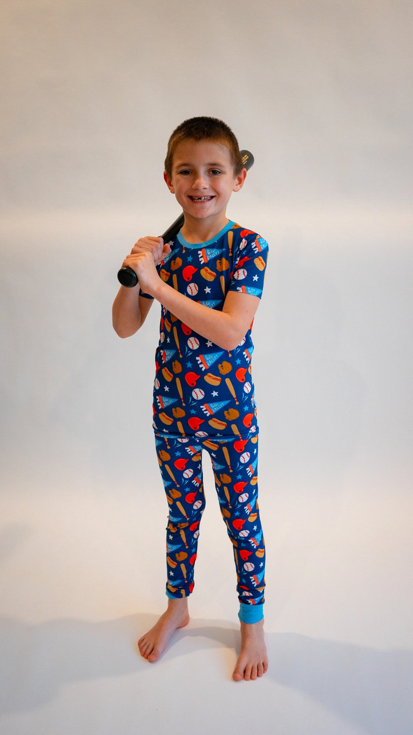 Boy holding baseball bat wearing Baseball Bamboo Two-Piece Pajamas with blue baseball print