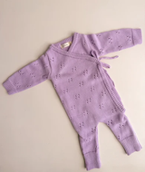 Baby wearing pointelle long romper in orchid, full-length view of long sleeves and relaxed fit