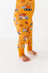Side detail of the Let the Gourd Times Roll footie showing pumpkin-and-truck print and ankle cuff.