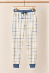 Fireside Windowpane ivory plaid adult pajama joggers with slate blue drawstring and cuffs on a wooden clip hanger against a creamy background