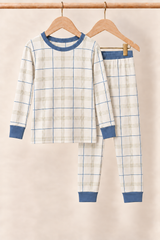 Fireside Windowpane ivory plaid kids two-piece pajamas with slate blue neckline, cuffs and pants waistband on wooden hangers against a creamy background