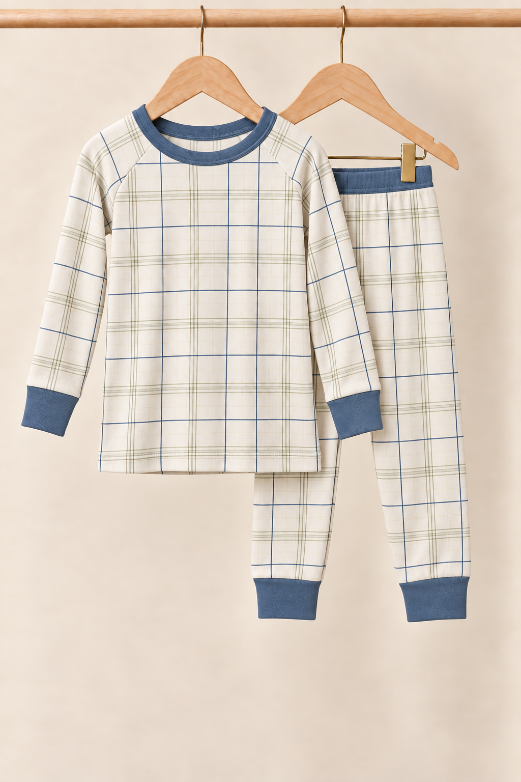 Fireside Windowpane ivory plaid toddler two-piece pajamas with slate blue trim on a wooden hanger against a creamy background