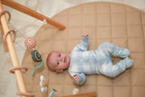 Baby in blue gingham romper lying on play mat - full body shot
