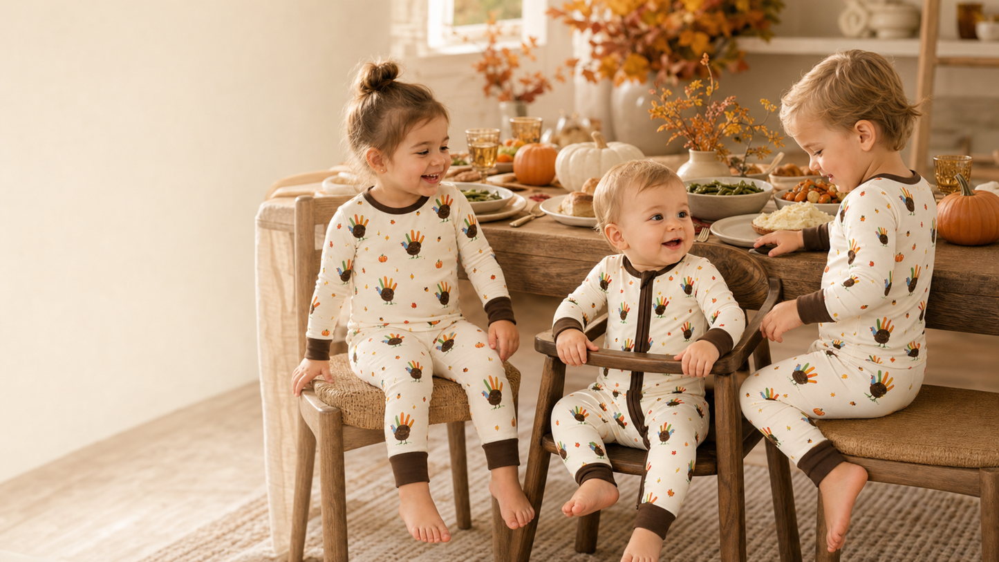 Babies and toddlers wearing Feathered Friend pajamas at a warm Thanksgiving dinner table