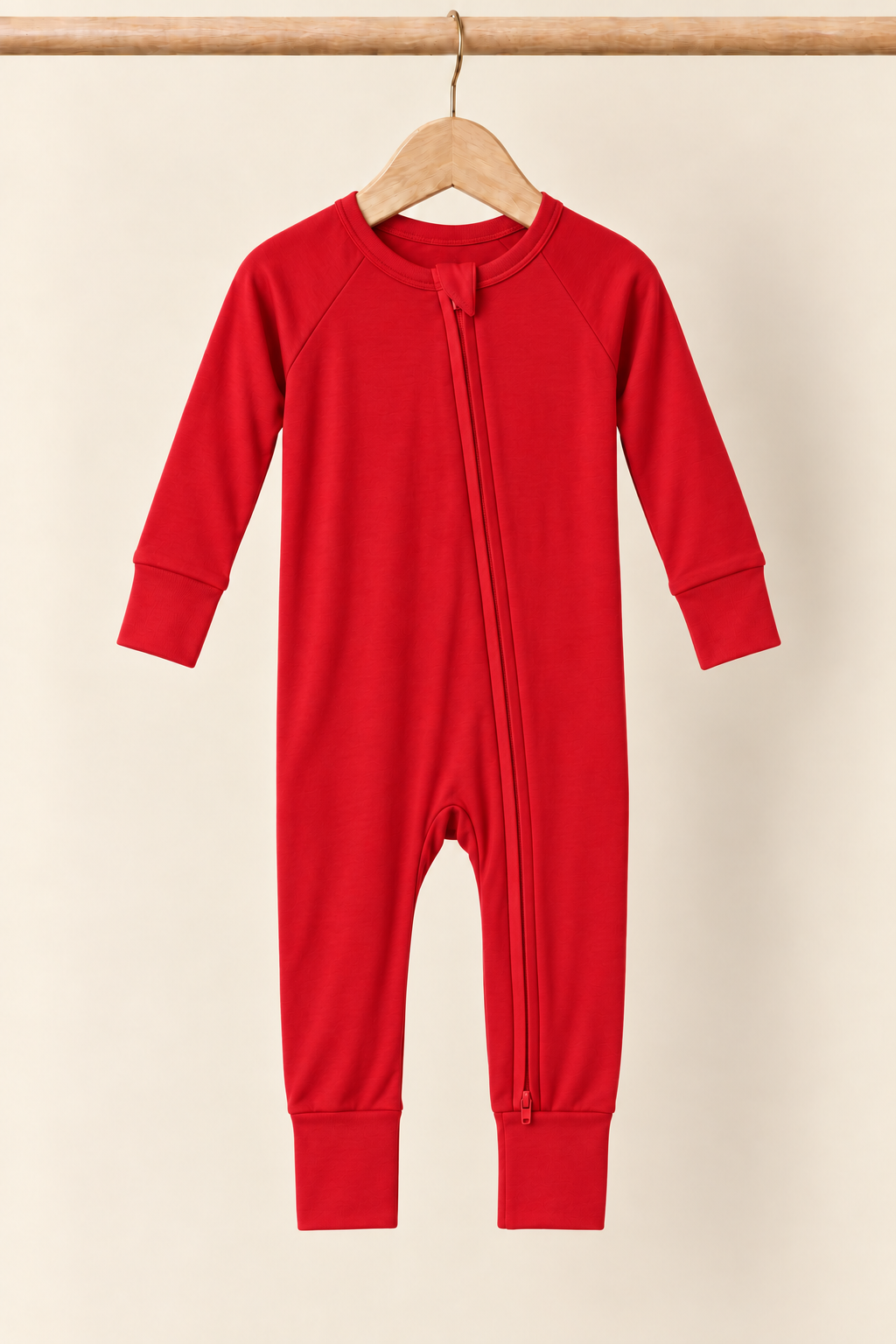 Holly Berry solid red convertible zippy pajamas on a wooden hanger against a creamy background