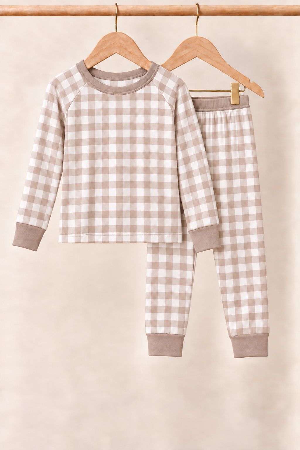 Mocha Gingham toddler two-piece pajamas with taupe trim on wooden hangers against a cream background