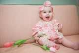 Happy baby girl laughing in pink rose floral romper with lace overlay and matching headband