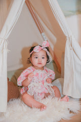 Toddler girl in pink rose floral romper with headband in teepee tent - full body shot