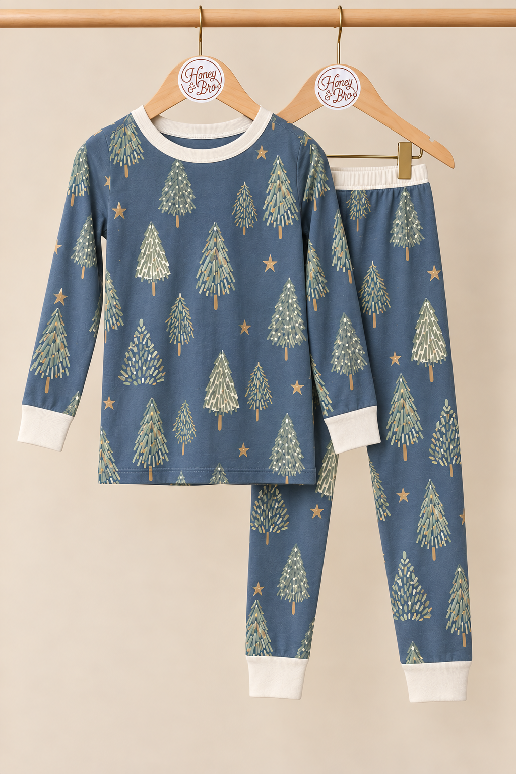 Starlit Evergreens toddler two-piece pajamas on wooden hangers with matching ivory trim against a creamy background