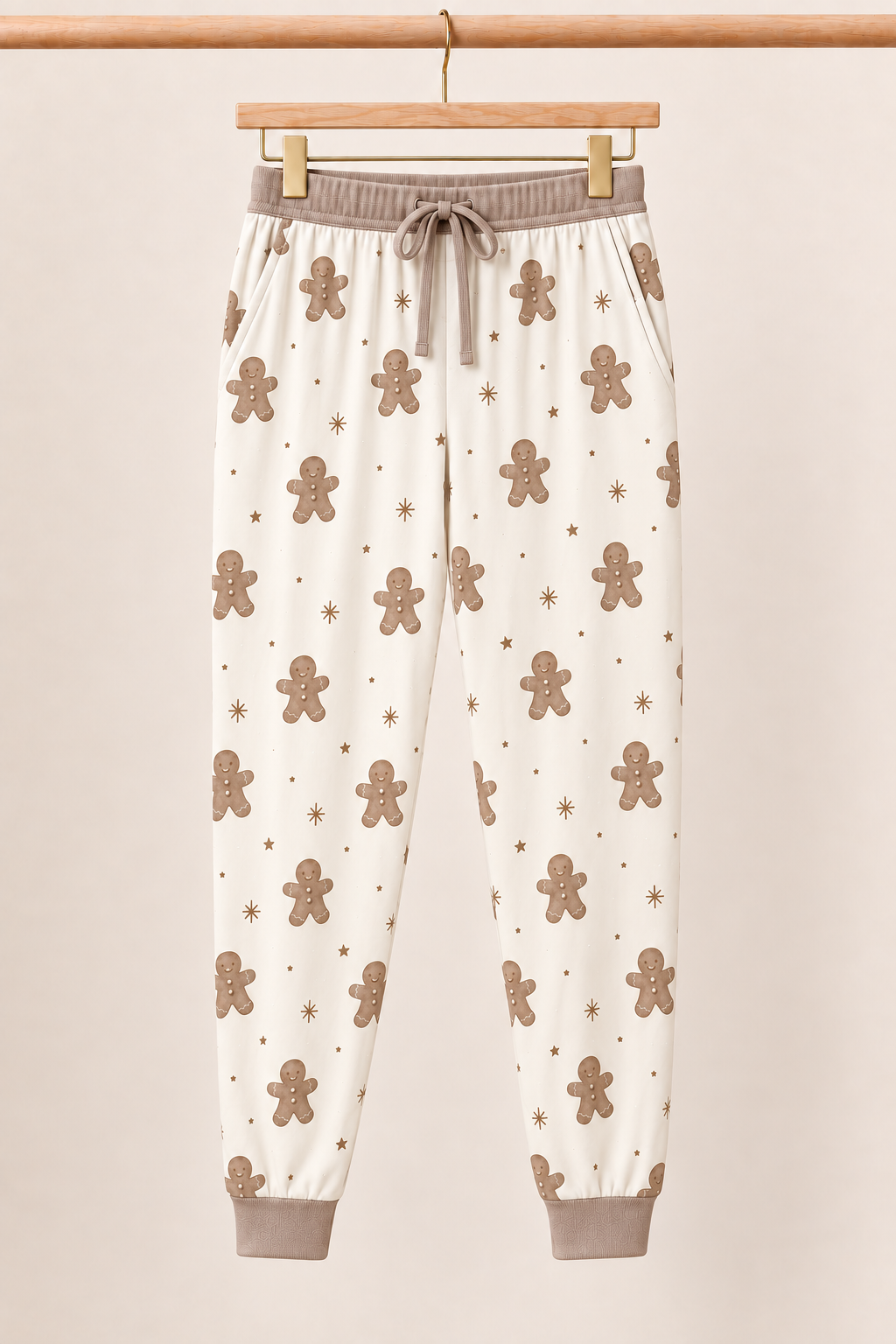 Winter Gingerbread Zinza™ Adult Pajama Jogger on wooden hangers against a warm cream background