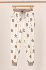 Winter Gingerbread Zinza™ Adult Pajama Jogger on wooden hangers against a warm cream background